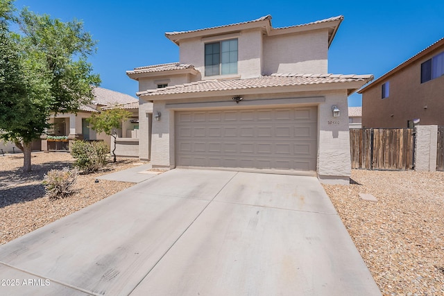 view of front of property with a tile roof, concrete driveway, stucco siding, and fence