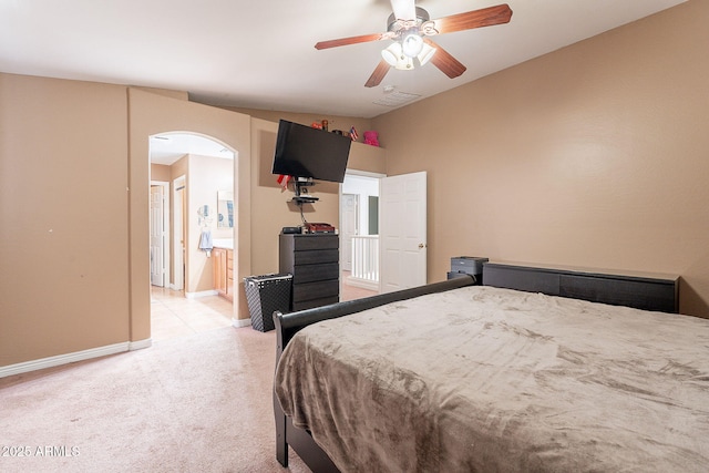 bedroom with visible vents, light carpet, arched walkways, connected bathroom, and baseboards
