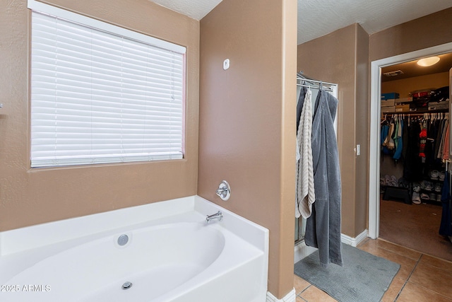 full bath with tile patterned flooring, a walk in closet, a garden tub, and a shower stall
