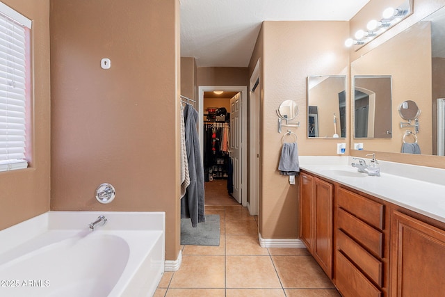 bathroom featuring vanity, tile patterned floors, a walk in closet, baseboards, and a bath