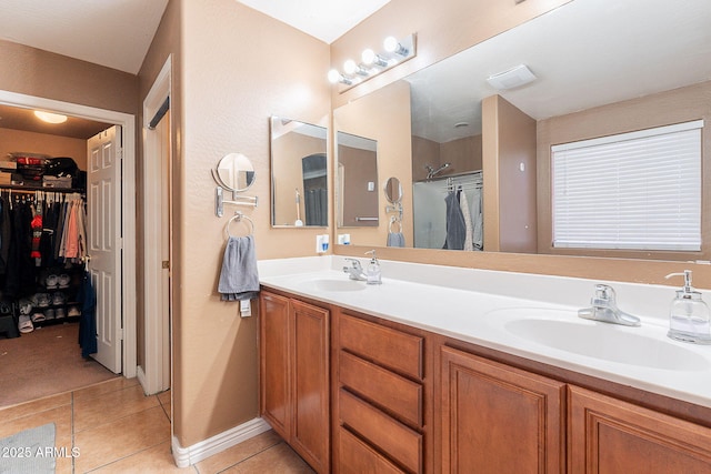 bathroom with a sink, a shower stall, tile patterned floors, double vanity, and a walk in closet