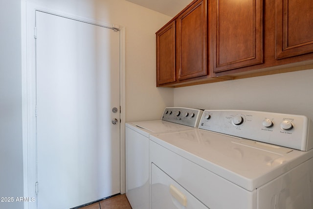 laundry room featuring light tile patterned flooring, cabinet space, and washer and clothes dryer