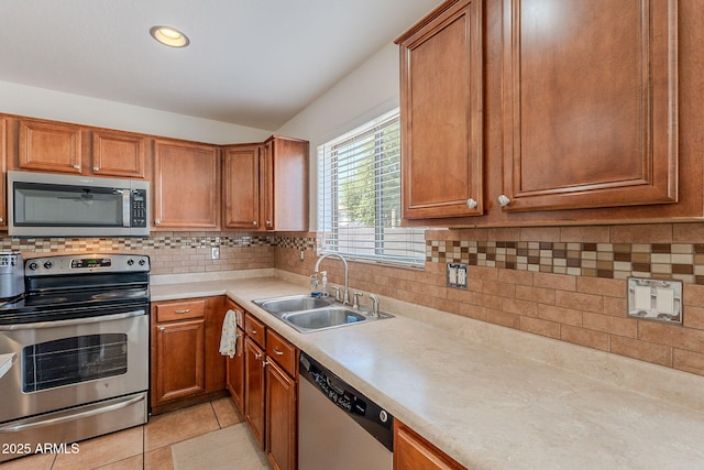 kitchen featuring brown cabinets, light countertops, appliances with stainless steel finishes, and a sink