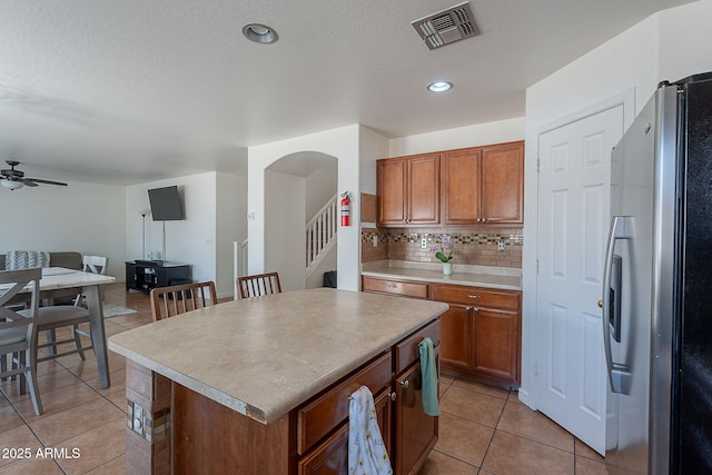 kitchen featuring freestanding refrigerator, light tile patterned floors, visible vents, and open floor plan