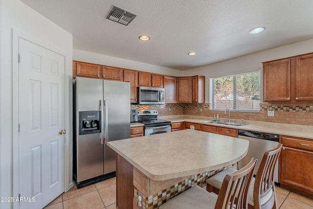 kitchen featuring stainless steel appliances, brown cabinetry, visible vents, and a sink