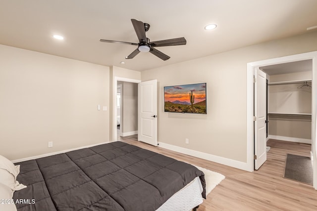 bedroom featuring ceiling fan, a spacious closet, and light wood-type flooring