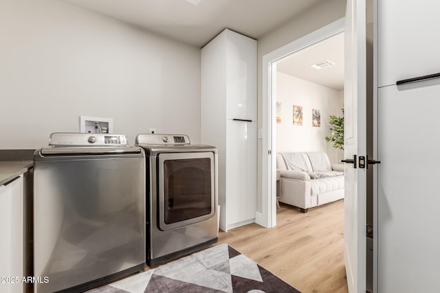 washroom with washer and clothes dryer and light hardwood / wood-style floors