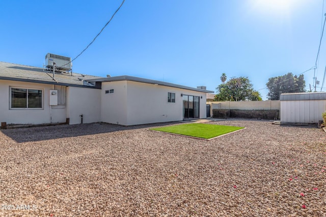 rear view of house with central AC and a storage unit