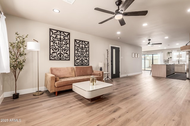 living room featuring sink, light hardwood / wood-style floors, and ceiling fan