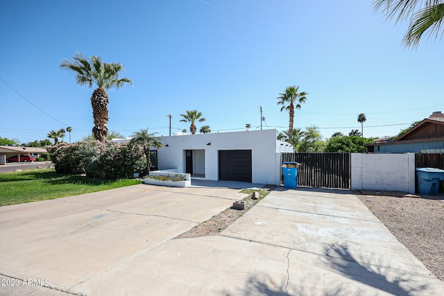 view of front of home with a gate, fence, stucco siding, concrete driveway, and a garage