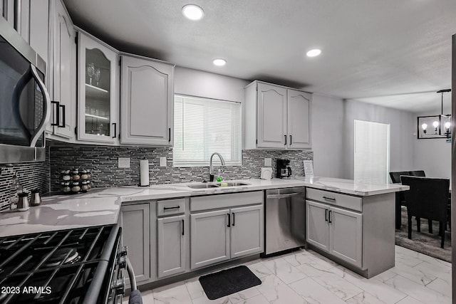 kitchen featuring gray cabinetry, appliances with stainless steel finishes, a peninsula, marble finish floor, and a sink