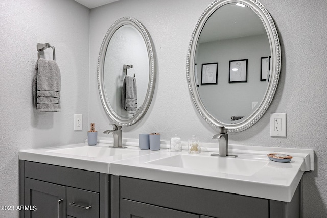 bathroom featuring double vanity, a textured wall, and a sink