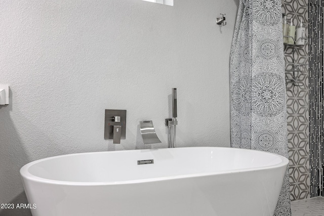 bathroom featuring a soaking tub and a textured wall