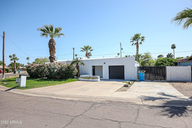 view of front of home with stucco siding, a gate, fence, concrete driveway, and an attached garage