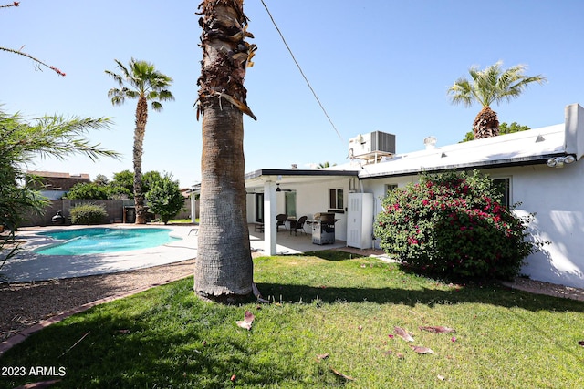 view of swimming pool featuring central AC unit, a fenced in pool, fence, a patio area, and a lawn