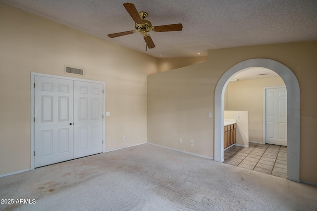 6101 E Beck Ln, Scottsdale, AZ 85254 - unfurnished bedroom featuring carpet, lofted ceiling, arched walkways, a textured ceiling, and ceiling fan