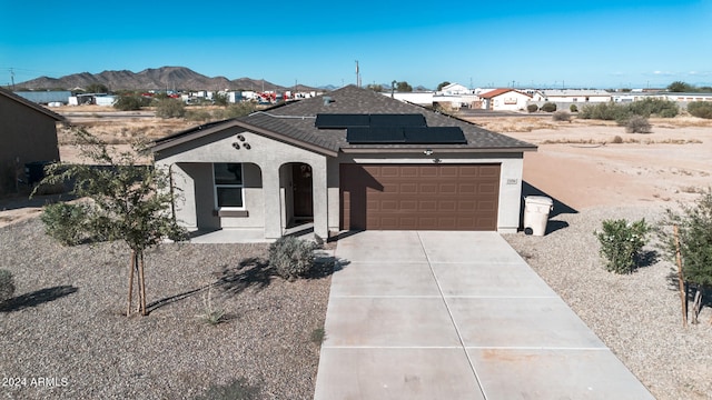 ranch-style house with a mountain view, solar panels, and a garage