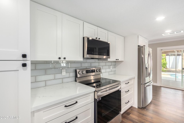 kitchen featuring light stone countertops, dark wood-type flooring, backsplash, white cabinetry, and appliances with stainless steel finishes