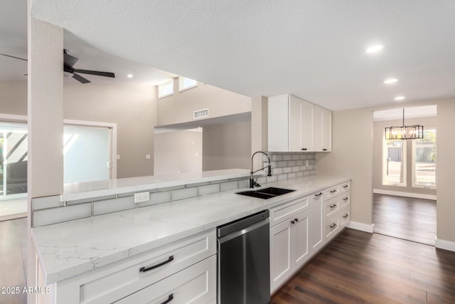 kitchen featuring light stone counters, decorative backsplash, white cabinets, stainless steel dishwasher, and sink