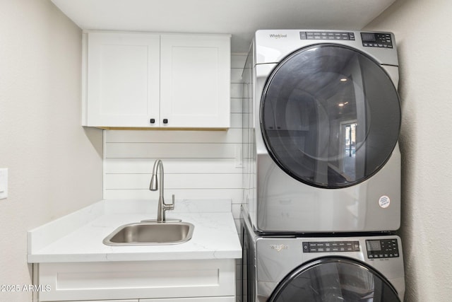 laundry room featuring sink, cabinets, and stacked washer / drying machine