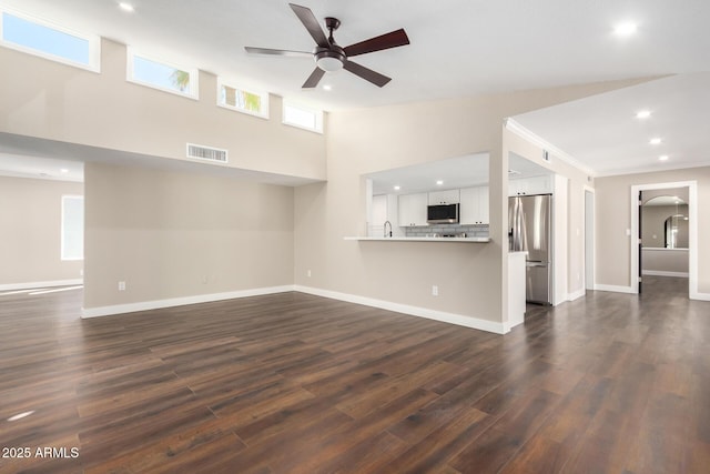 unfurnished living room with ceiling fan, dark hardwood / wood-style flooring, and a towering ceiling