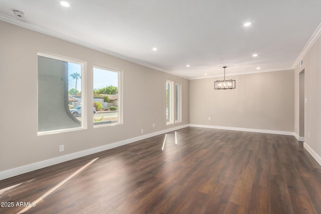 spare room featuring dark wood-type flooring, crown molding, and a chandelier