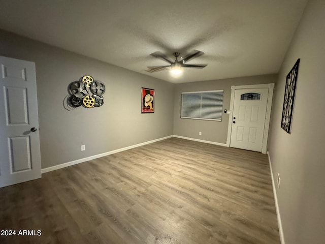 spare room with a ceiling fan, wood finished floors, baseboards, and a textured ceiling