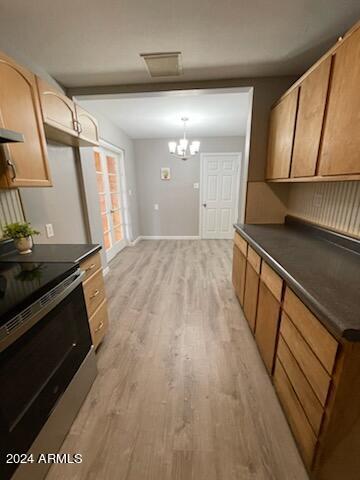 kitchen featuring light wood-style flooring, dark countertops, an inviting chandelier, stainless steel electric range oven, and baseboards