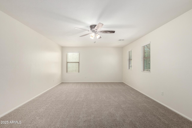 empty room featuring baseboards, a ceiling fan, and light carpet