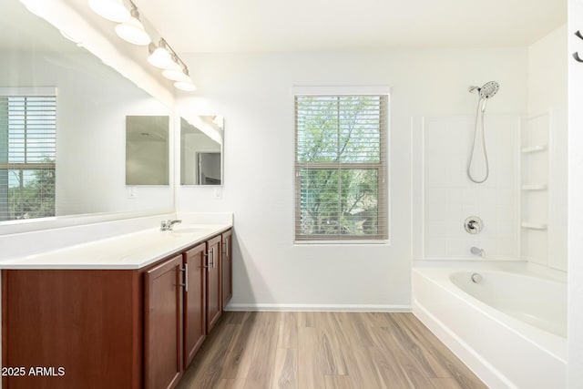 full bath featuring baseboards, wood finished floors, shower / bathing tub combination, and vanity