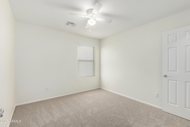 carpeted spare room with visible vents, a ceiling fan, and baseboards