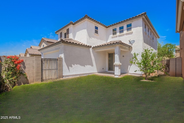 rear view of property featuring a tiled roof, a yard, a fenced backyard, and stucco siding