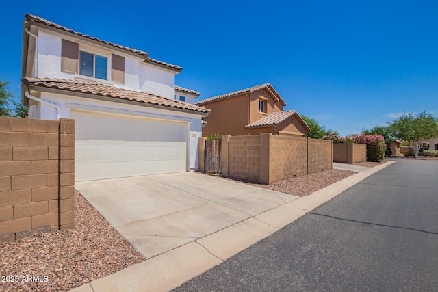 mediterranean / spanish house with a garage, fence, stucco siding, a tiled roof, and driveway