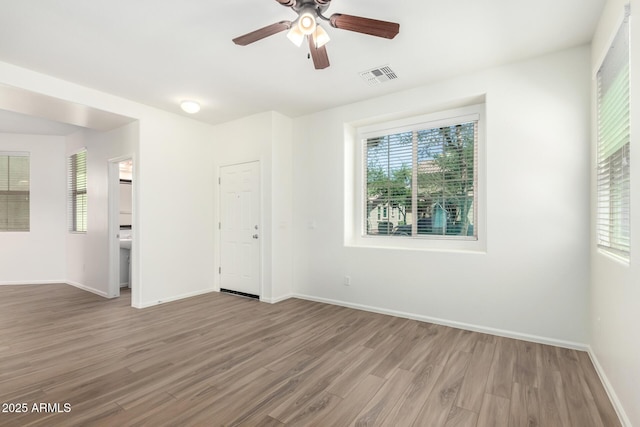 spare room with a ceiling fan, visible vents, a wealth of natural light, and wood finished floors
