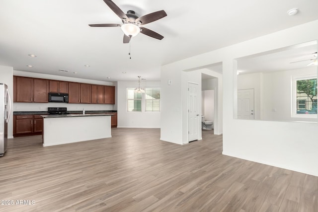 kitchen with dark countertops, a ceiling fan, black appliances, and open floor plan