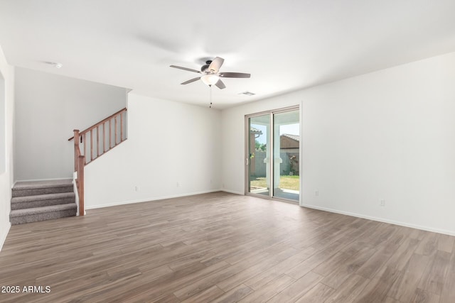 unfurnished living room with ceiling fan, stairs, wood finished floors, and visible vents
