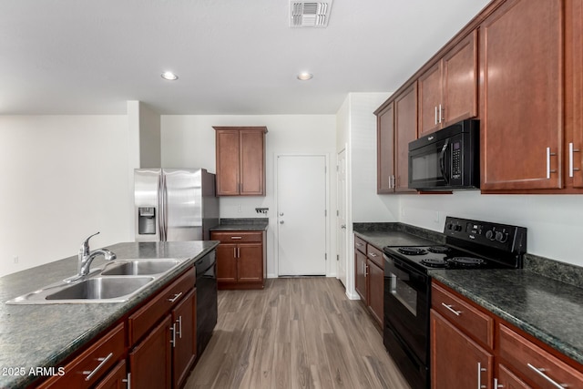 kitchen with visible vents, dark countertops, a sink, black appliances, and light wood-style flooring