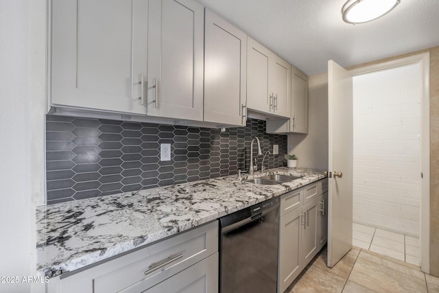 kitchen featuring dishwasher, sink, tasteful backsplash, light tile patterned flooring, and light stone counters