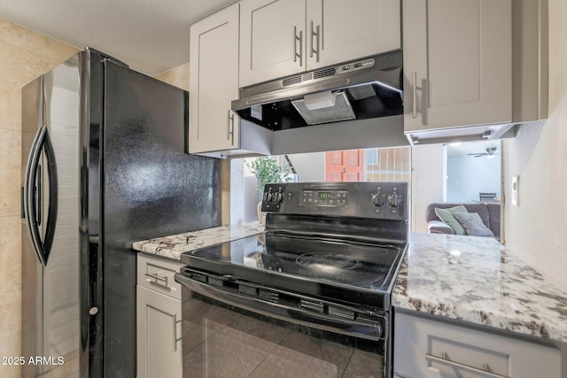 kitchen featuring tile patterned floors, refrigerator, ceiling fan, light stone countertops, and black range with electric cooktop