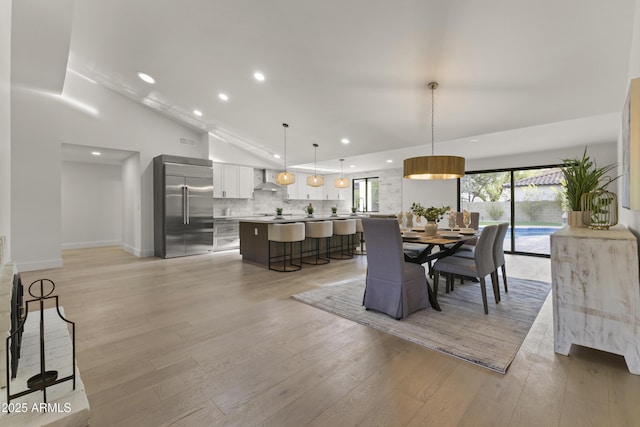 dining area featuring high vaulted ceiling and light hardwood / wood-style flooring