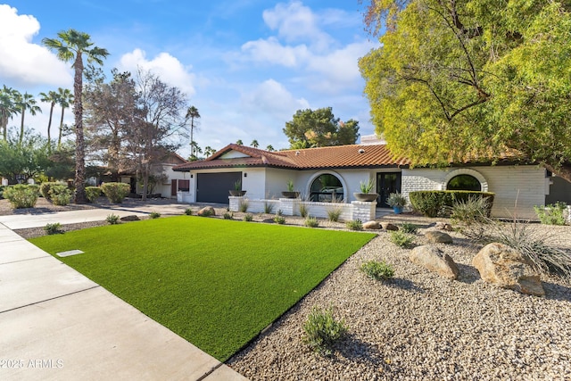 mediterranean / spanish-style house featuring a garage and a front yard