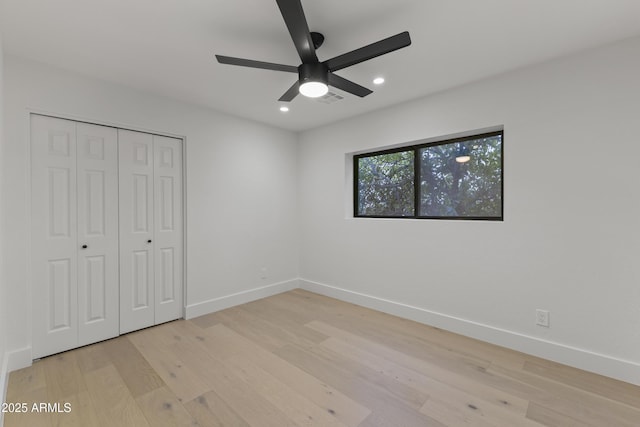 unfurnished bedroom with ceiling fan, a closet, and light wood-type flooring