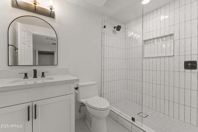 bathroom featuring vanity, toilet, and a tile shower