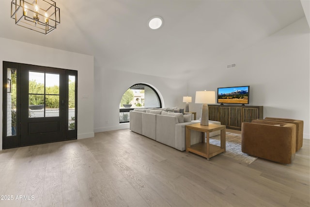 living room featuring an inviting chandelier, light hardwood / wood-style flooring, and high vaulted ceiling