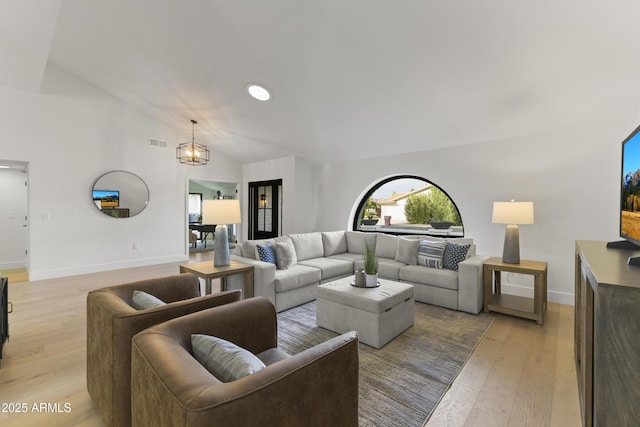 living room with a notable chandelier, light hardwood / wood-style floors, and high vaulted ceiling