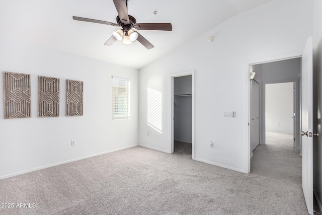 unfurnished bedroom with lofted ceiling, a walk in closet, light carpet, and ceiling fan