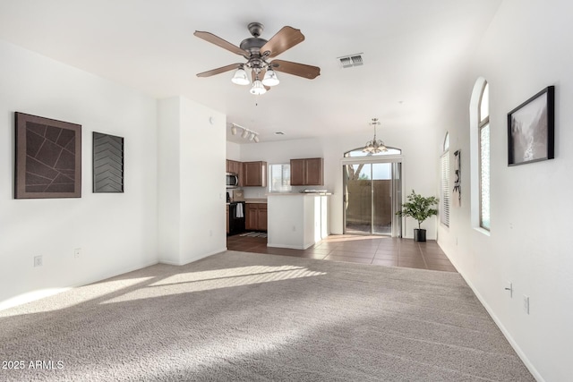 unfurnished living room with ceiling fan and dark colored carpet