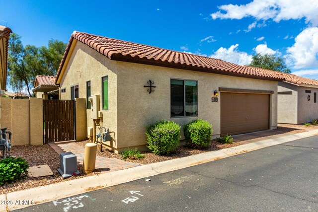 4495 E Woodside Way, Gilbert, AZ 85297 - mediterranean / spanish house featuring a garage, a tiled roof, a gate, and stucco siding
