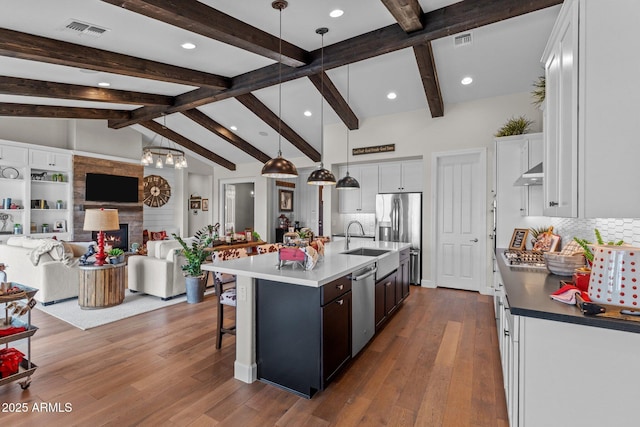 kitchen with visible vents, stainless steel appliances, wall chimney exhaust hood, open floor plan, and a large fireplace