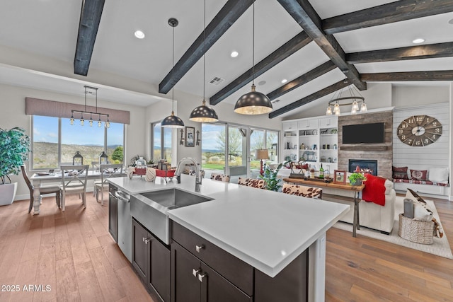 kitchen featuring a sink, a large fireplace, open floor plan, and light countertops